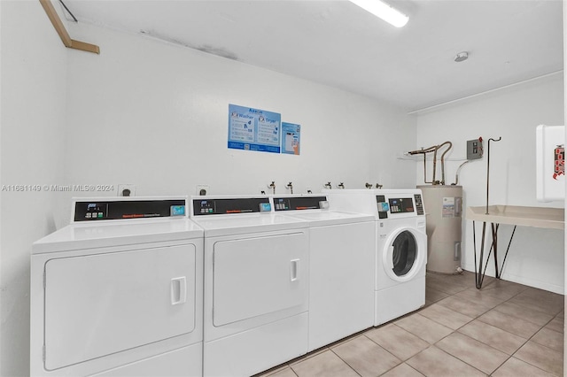 clothes washing area featuring light tile patterned flooring, electric water heater, and washing machine and clothes dryer