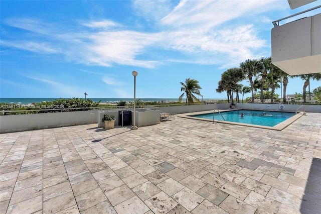 view of pool with a patio and a water view