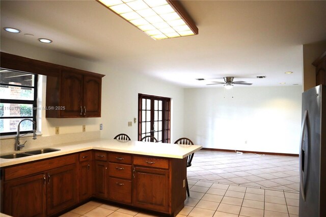 kitchen with kitchen peninsula, sink, light tile patterned floors, and ceiling fan