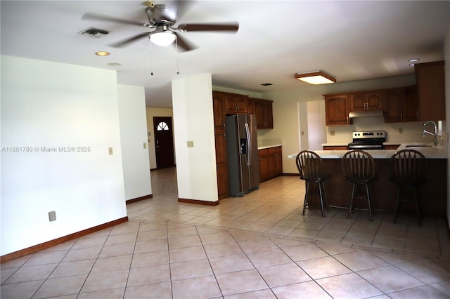 kitchen with stainless steel appliances, light countertops, light tile patterned flooring, a sink, and a peninsula