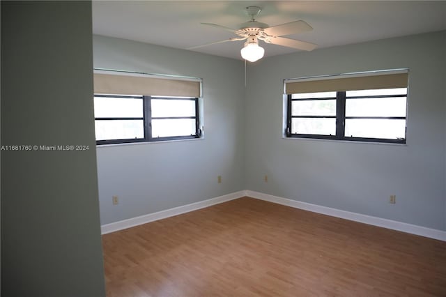 empty room with a healthy amount of sunlight, wood-type flooring, and ceiling fan