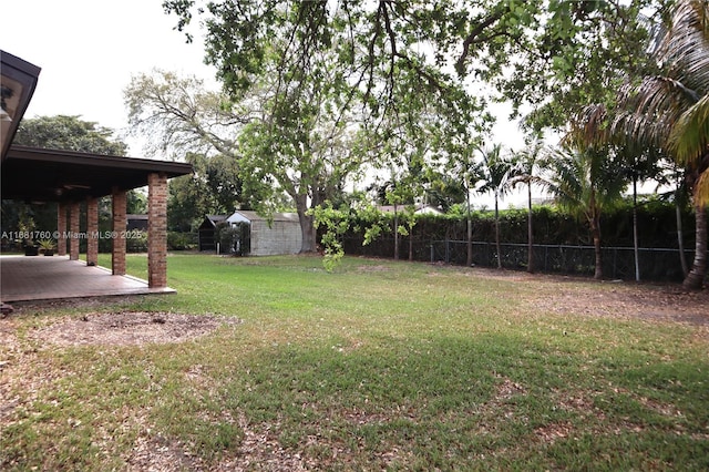 view of yard with a storage unit, fence, a patio, and an outdoor structure