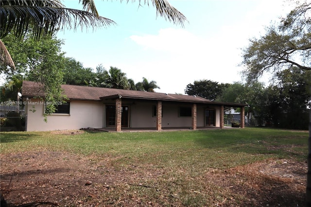 view of front of home with a front lawn, a patio, and stucco siding