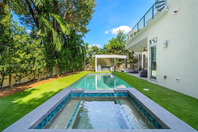 view of swimming pool featuring ceiling fan, a yard, and an in ground hot tub