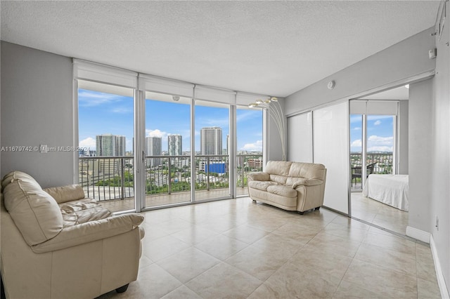 living room with a wall of windows, a textured ceiling, and light tile patterned floors