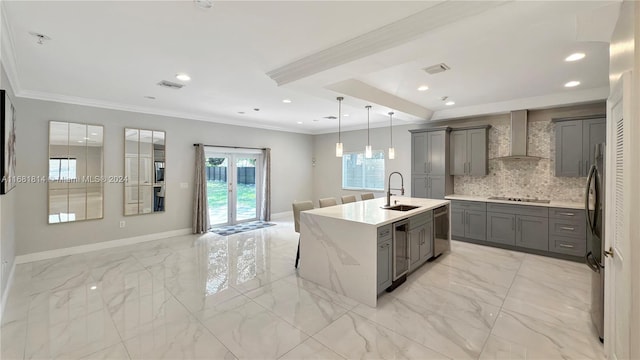 kitchen featuring hanging light fixtures, sink, a kitchen breakfast bar, wall chimney exhaust hood, and a kitchen island with sink