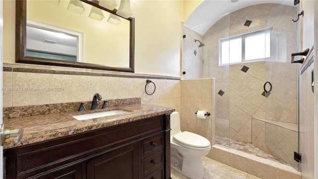 bathroom featuring walk in shower, vanity, toilet, and tile walls