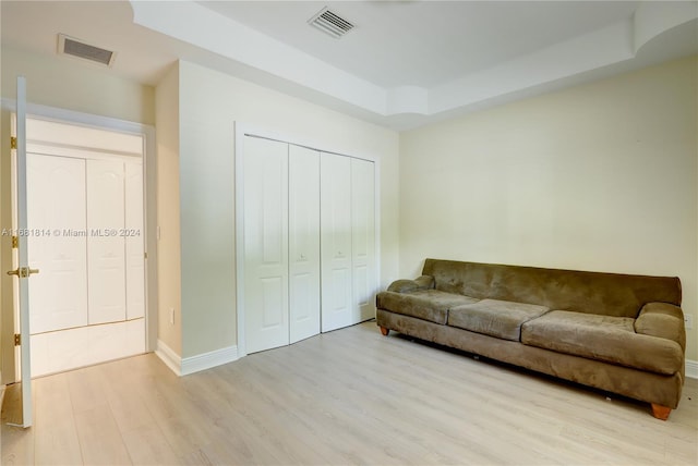 living room with a raised ceiling and light hardwood / wood-style flooring