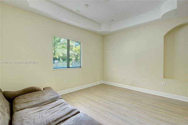 living area with light hardwood / wood-style flooring and a raised ceiling