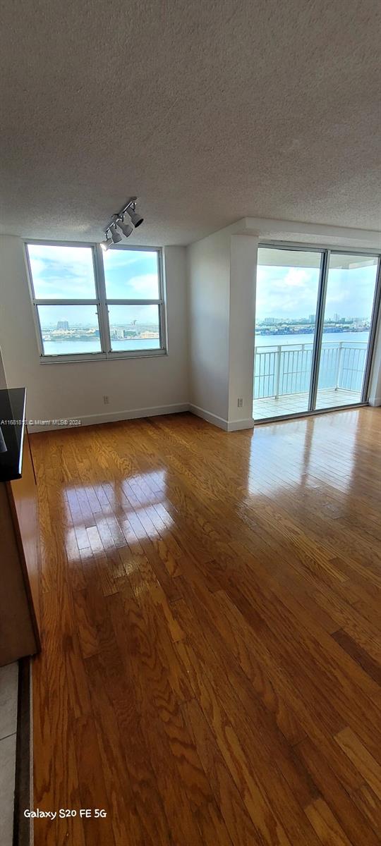 empty room with light hardwood / wood-style flooring, a textured ceiling, and a water view