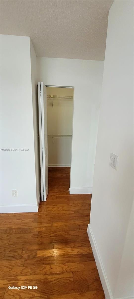 corridor featuring hardwood / wood-style floors and a textured ceiling