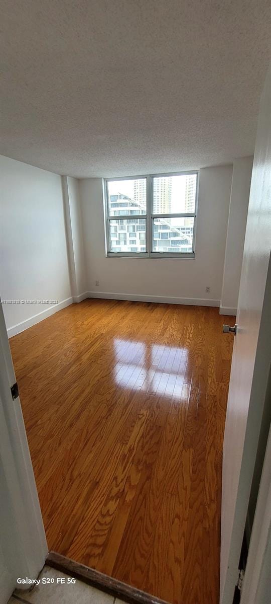 unfurnished room featuring a textured ceiling and hardwood / wood-style floors