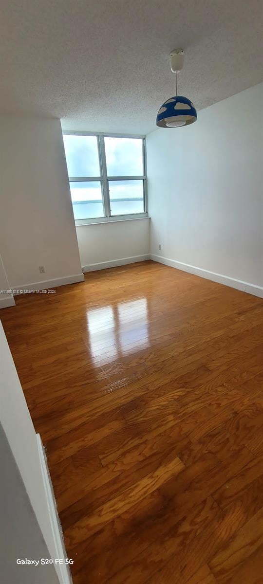 empty room with hardwood / wood-style floors and a textured ceiling