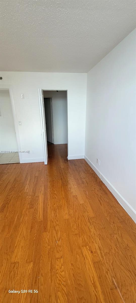 unfurnished room featuring a textured ceiling and light wood-type flooring