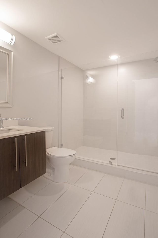 bathroom with vanity, tile patterned flooring, toilet, and a shower with door