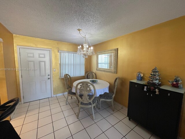 dining area featuring light tile patterned floors, a textured ceiling, and an inviting chandelier