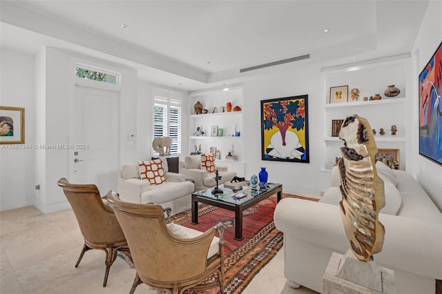 living room with a raised ceiling and built in shelves