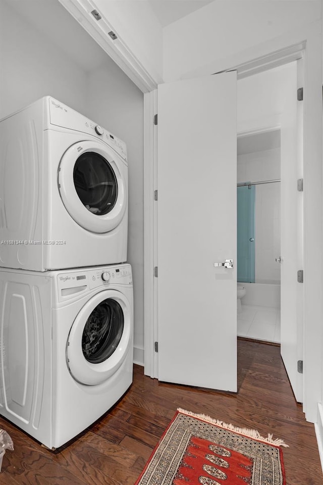 laundry room featuring dark wood-type flooring and stacked washing maching and dryer