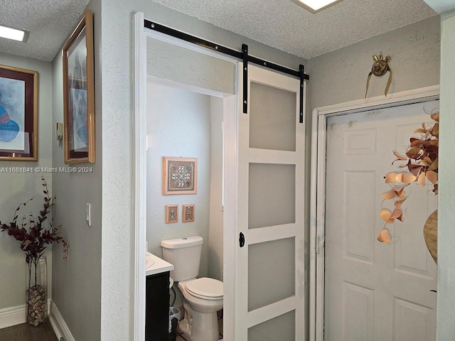 bathroom with vanity, toilet, and a textured ceiling