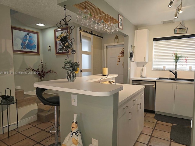 kitchen with stainless steel dishwasher, a barn door, white cabinetry, and a kitchen island