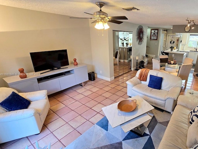 living room featuring ceiling fan, light tile patterned flooring, and a textured ceiling