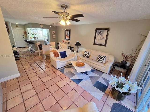 living room featuring ceiling fan, light tile patterned floors, and a textured ceiling