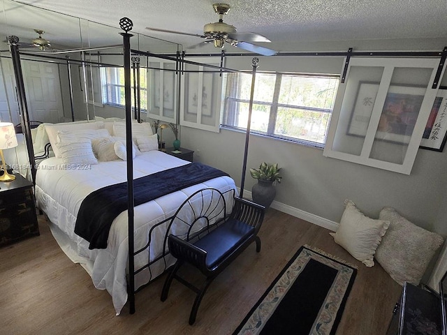 bedroom with hardwood / wood-style floors, ceiling fan, a barn door, and a textured ceiling