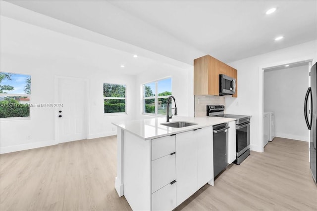 kitchen with decorative backsplash, appliances with stainless steel finishes, sink, light hardwood / wood-style flooring, and white cabinetry