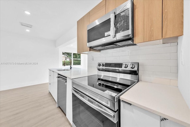 kitchen featuring backsplash, light hardwood / wood-style floors, sink, and stainless steel appliances