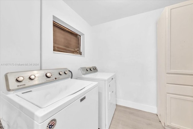 clothes washing area with light hardwood / wood-style flooring and washer and dryer