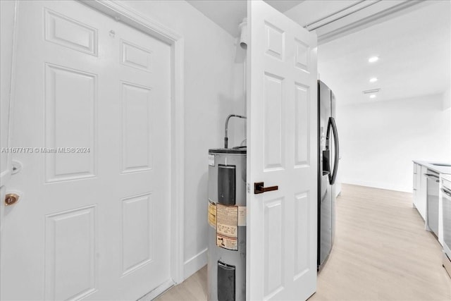 kitchen featuring light hardwood / wood-style floors, electric water heater, stainless steel appliances, and white cabinetry