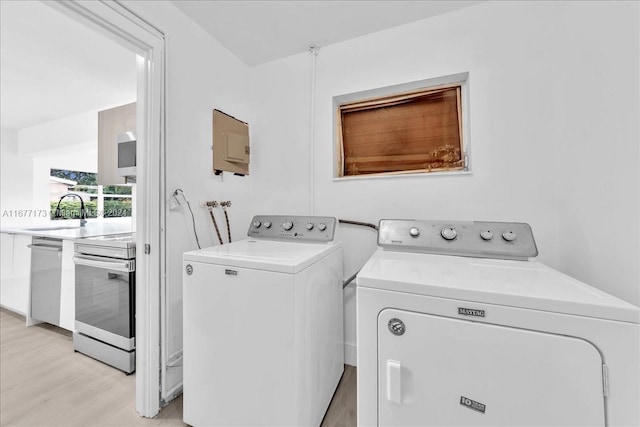 laundry room featuring washing machine and dryer, sink, and light hardwood / wood-style floors