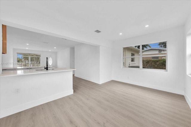 unfurnished living room with light hardwood / wood-style flooring and sink