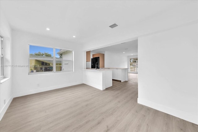 unfurnished living room featuring sink and light hardwood / wood-style flooring