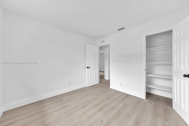 unfurnished bedroom with light wood-type flooring and a closet