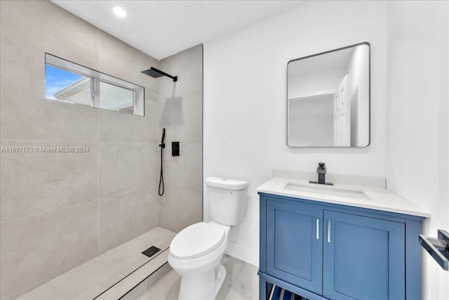 bathroom featuring tiled shower, vanity, and toilet