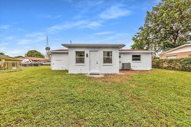 rear view of property with central air condition unit and a lawn