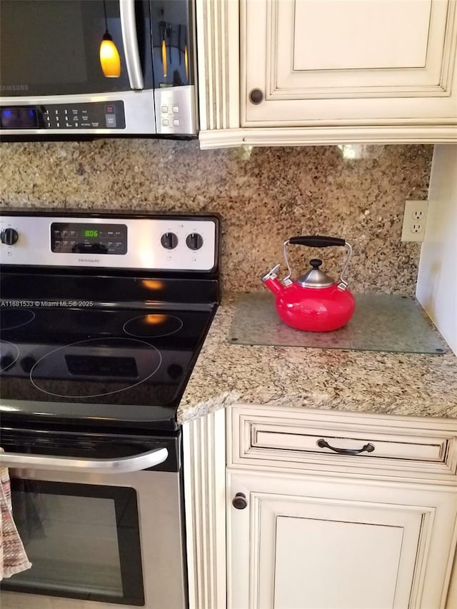 kitchen with stainless steel appliances, cream cabinetry, tasteful backsplash, and light stone countertops