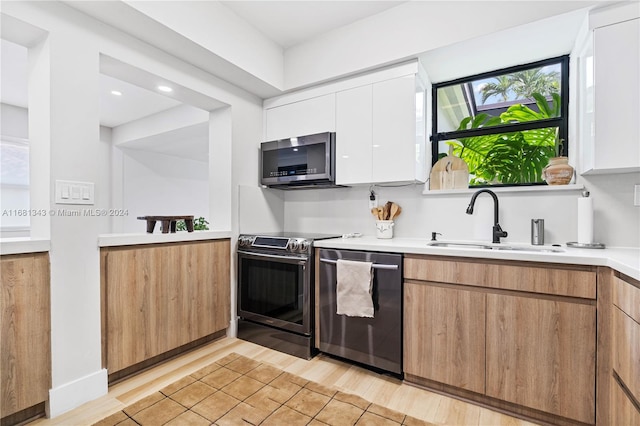 kitchen featuring sink, white cabinets, stainless steel appliances, and light hardwood / wood-style flooring