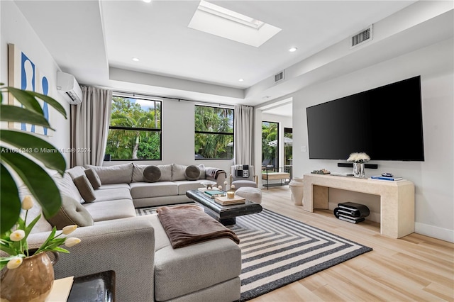 living room with light wood-type flooring, a wall unit AC, and a skylight