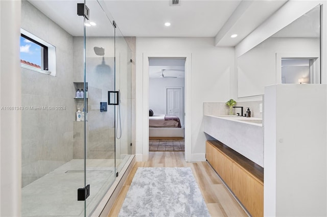 bathroom with hardwood / wood-style floors, vanity, ceiling fan, and a shower with door