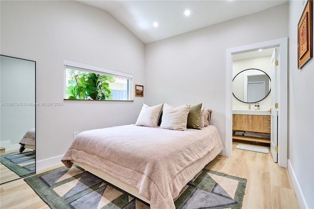 bedroom featuring light wood-type flooring, connected bathroom, and vaulted ceiling