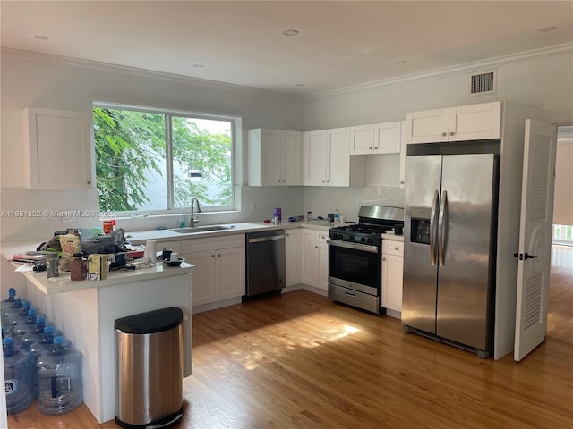 kitchen featuring sink, white cabinetry, appliances with stainless steel finishes, kitchen peninsula, and hardwood / wood-style floors