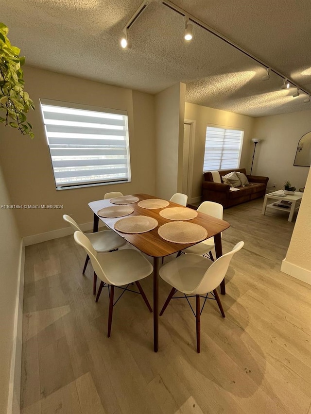 dining area featuring light hardwood / wood-style floors, a textured ceiling, and rail lighting