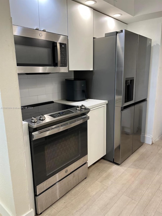 kitchen with decorative backsplash, appliances with stainless steel finishes, and light wood-type flooring