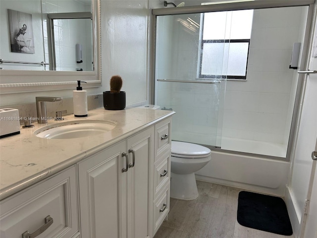 full bathroom featuring vanity, toilet, hardwood / wood-style flooring, and enclosed tub / shower combo