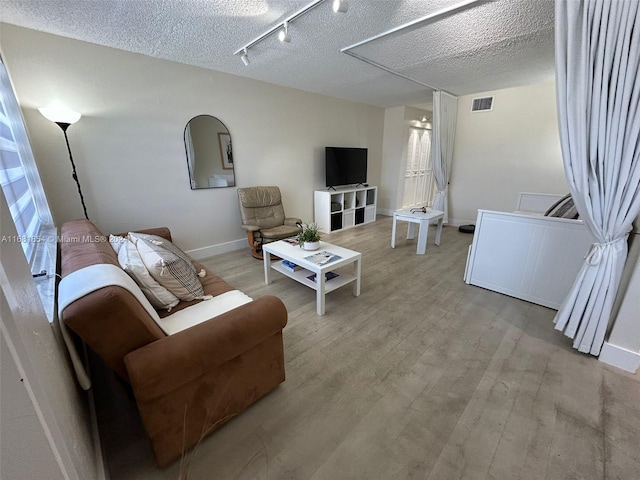 living room with rail lighting, a textured ceiling, and light wood-type flooring