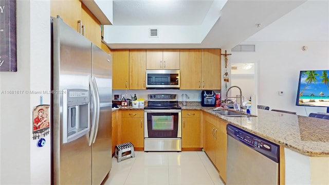 kitchen with sink, light stone countertops, light tile patterned floors, kitchen peninsula, and stainless steel appliances