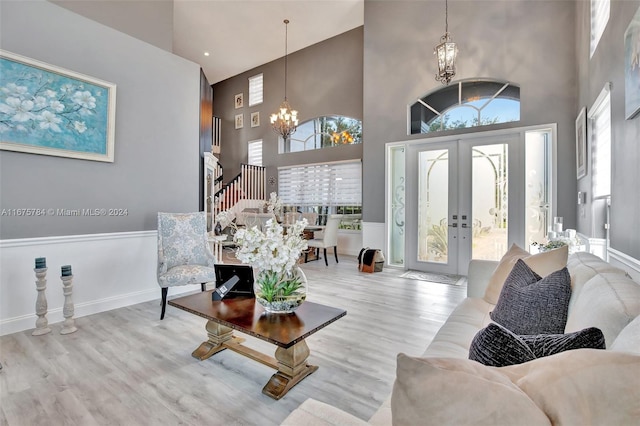 interior space featuring french doors, a notable chandelier, a high ceiling, and light wood-type flooring