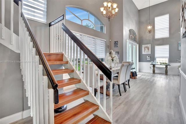 stairway featuring a notable chandelier, a towering ceiling, and hardwood / wood-style floors